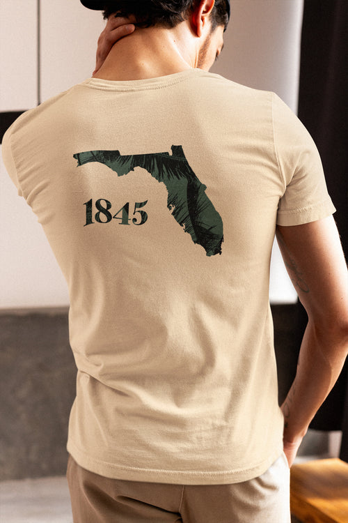 Person wearing a beige t-shirt with a graphic of Florida and the year 1845 on the back.