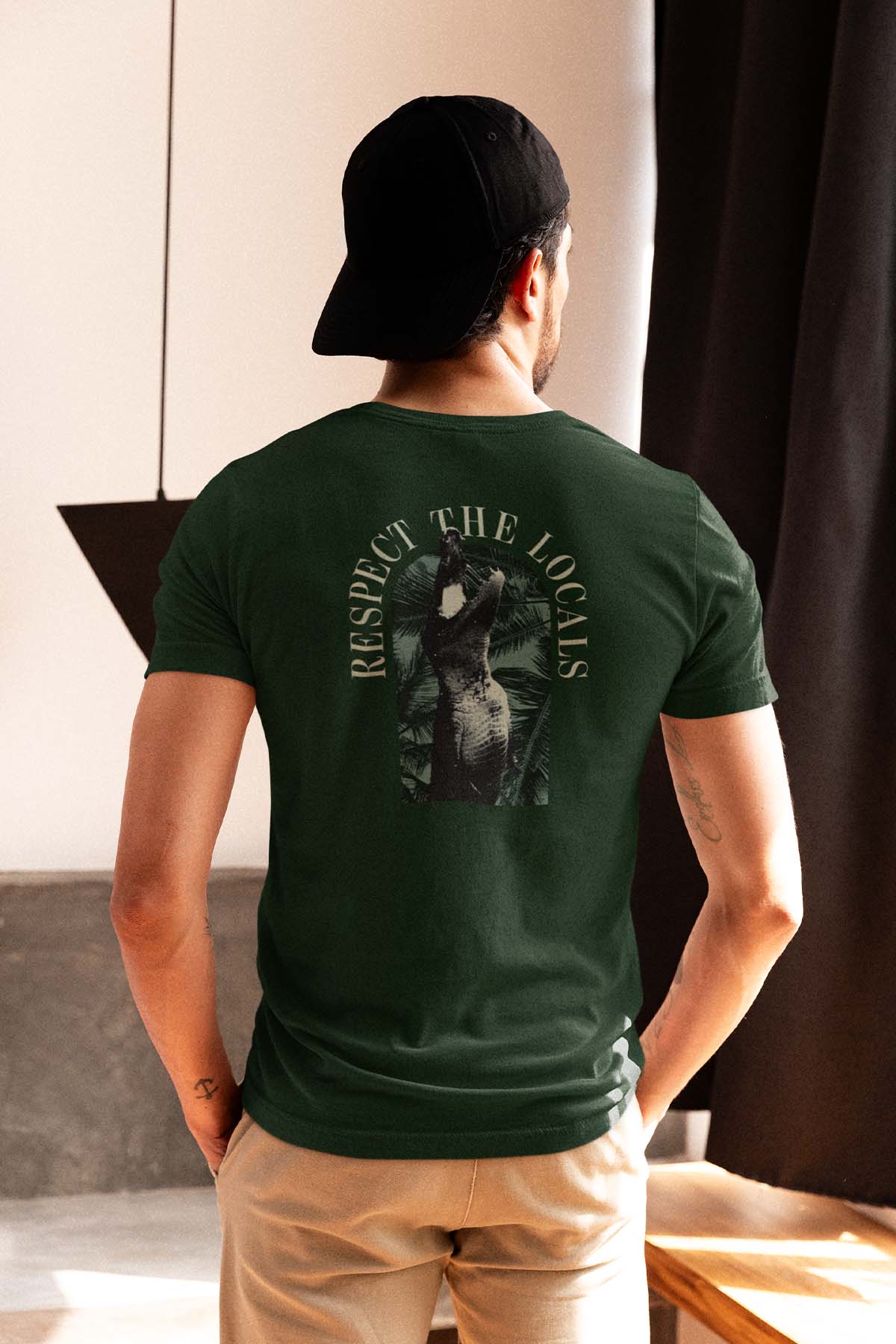 Man wearing dark green t-shirt with alligator and 'Respect The Locals' text on back